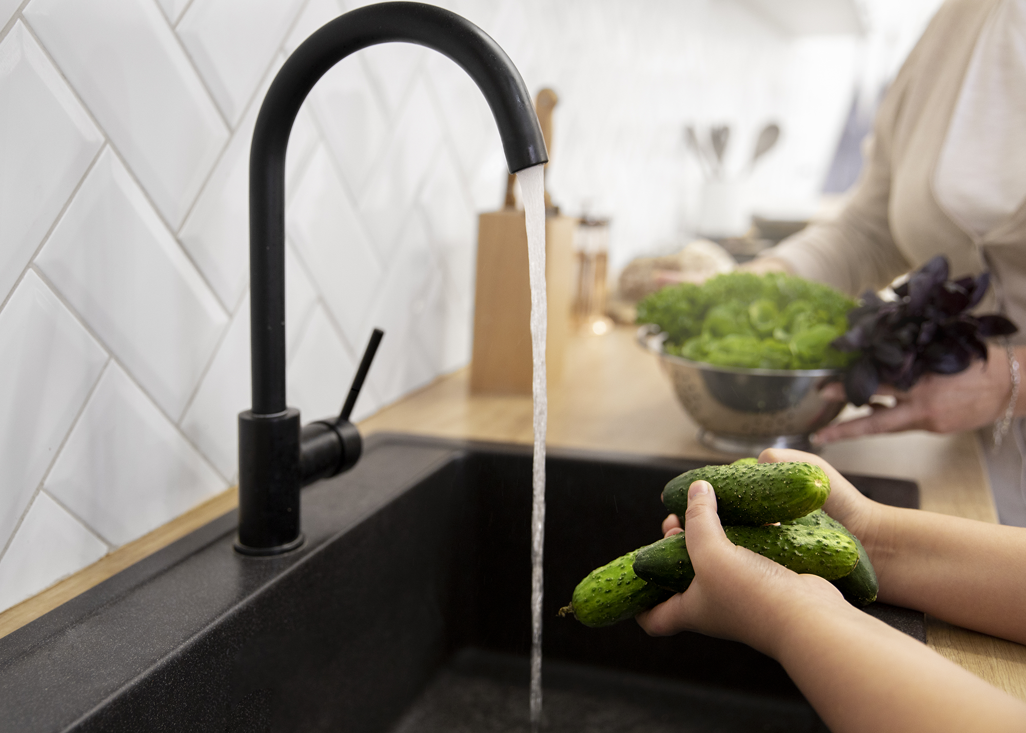 Limpiando zanahorias y otras verduras en el grifo de la cocina