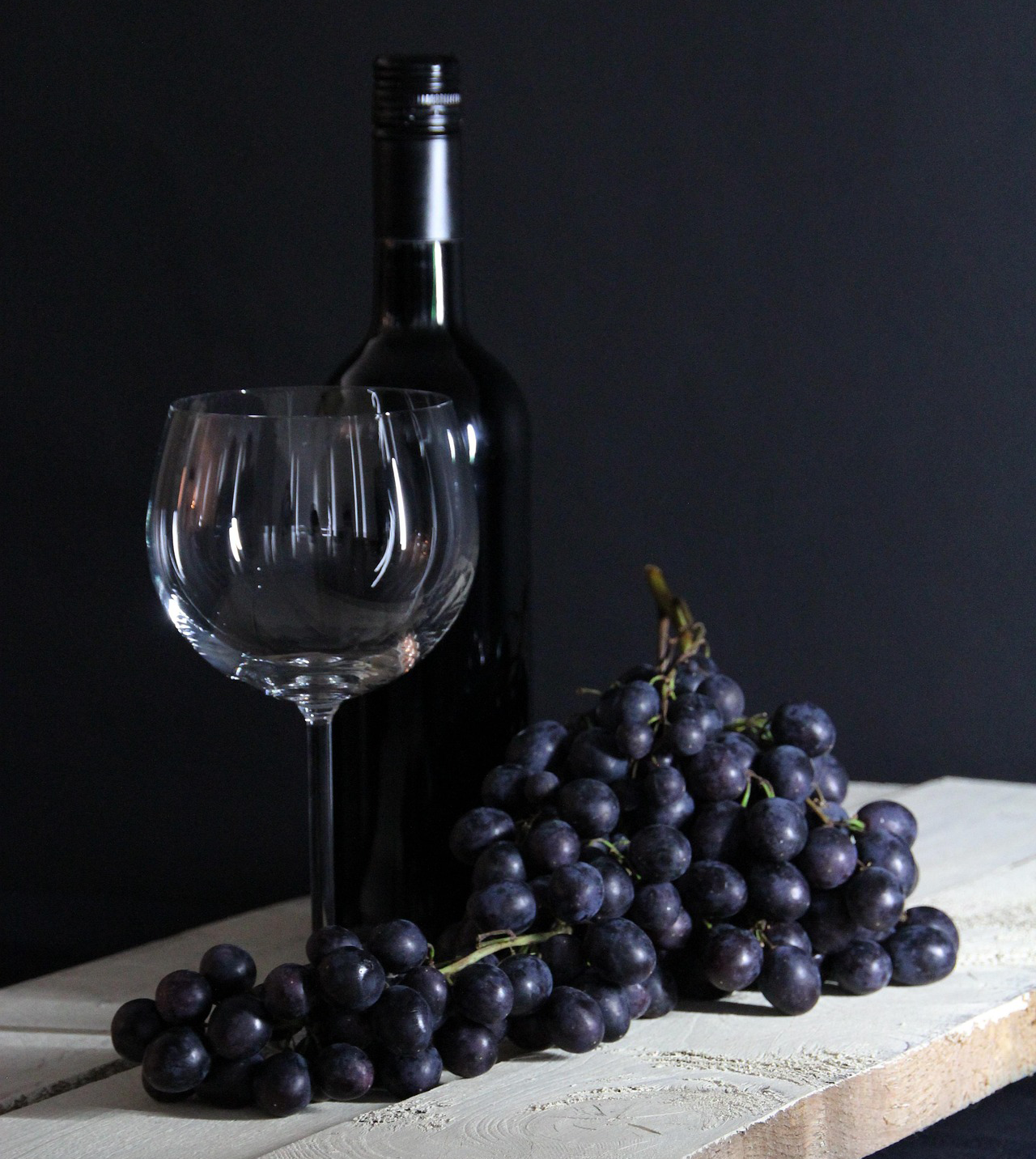 Botella de vino, con una copa y uvas delante Botella de vino, con una copa y uvas delante